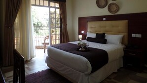 A hotel room with a large bed, a nightstand, a chair, and a window with curtains. - Villa Leone (Nairobi)