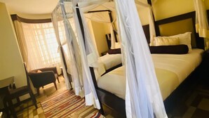 A room with a bed under a canopy, a sofa, and a patterned rug. - Villa Leone (Nairobi)