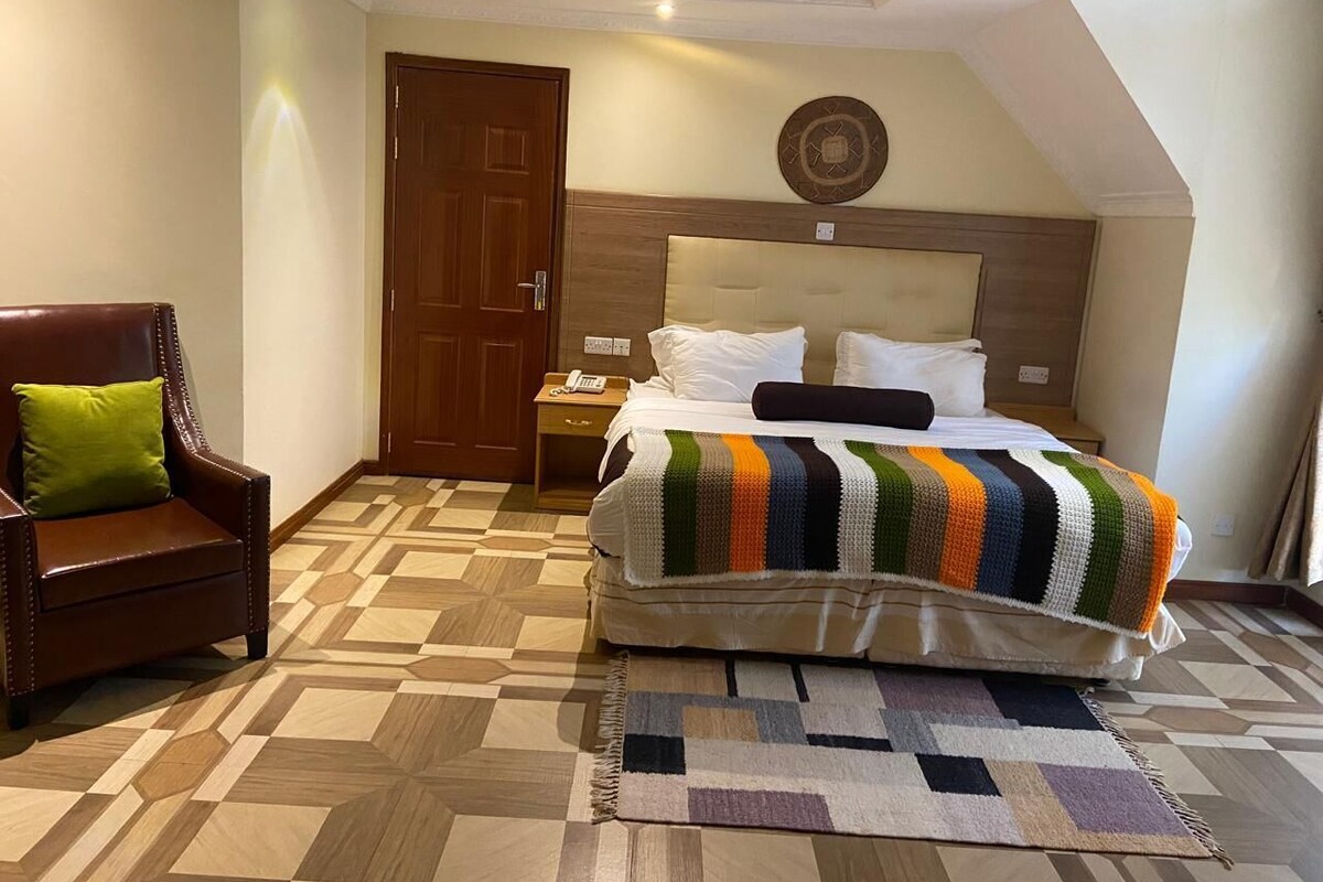 A bedroom with a bed, a nightstand, a chair, and a door.