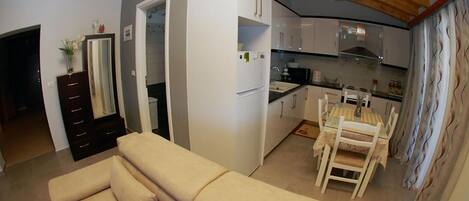 Ein kompakter Wohnbereich mit Küchenzeile, Essplatz und Sofa.