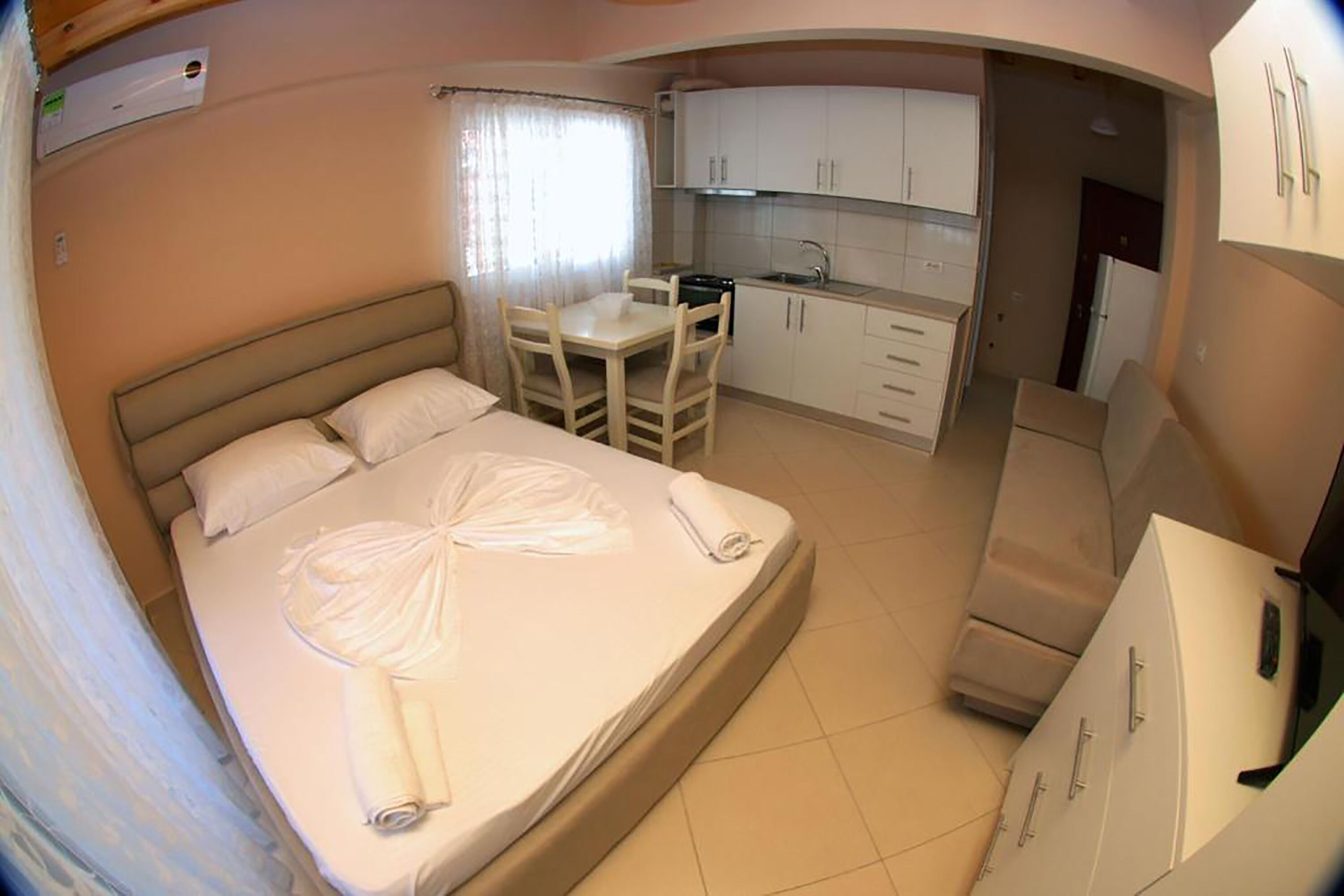 A compact room with a bed, a small table, and a kitchenette.