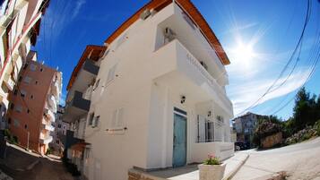 A narrow street with a white building featuring a blue door and a balcony.