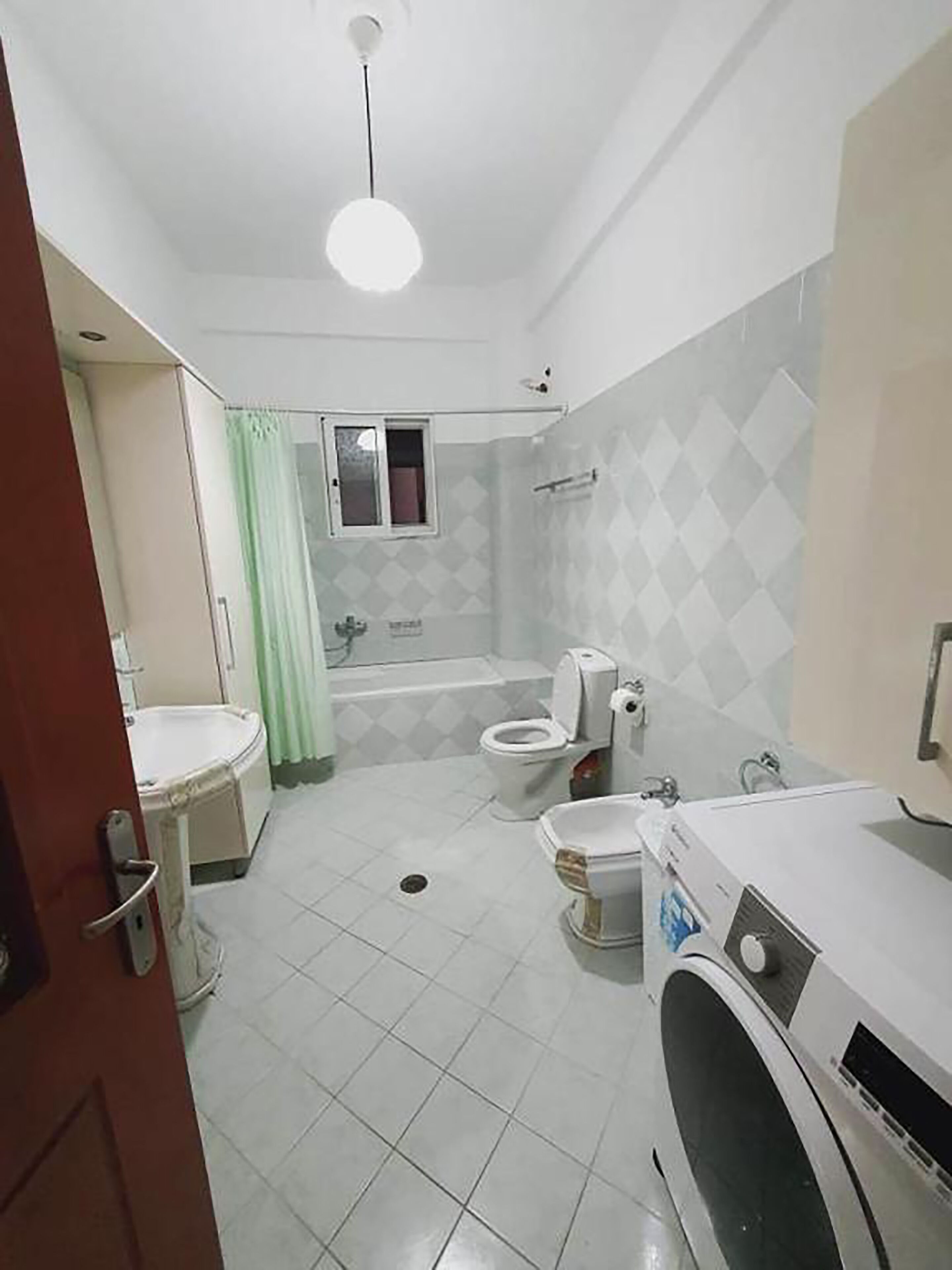 A bathroom with a toilet, bidet, sink, and washing machine.
