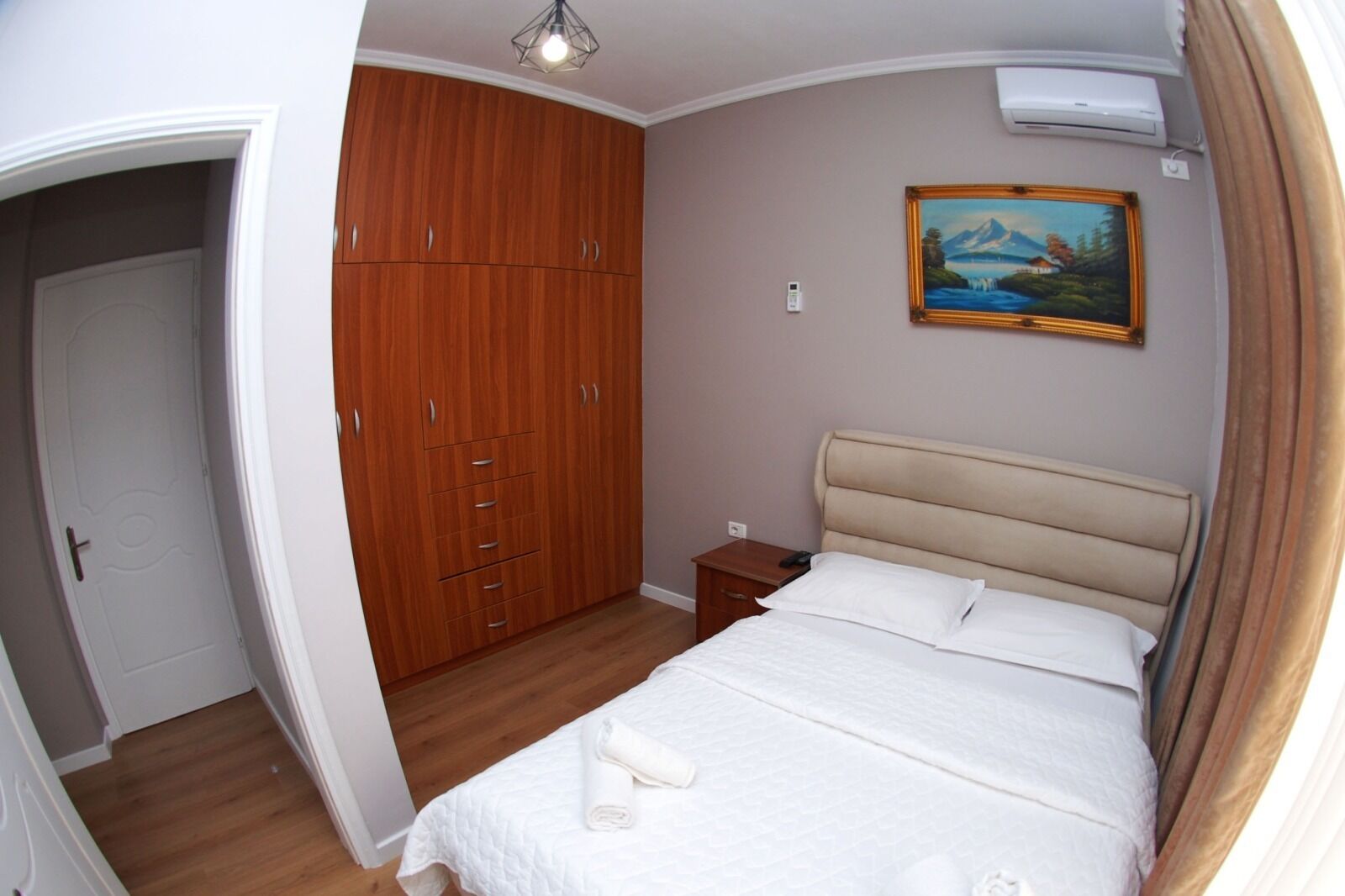 Ein Schlafzimmer mit Bett, Kleiderschrank, Nachttisch und einem Gemälde an der Wand.