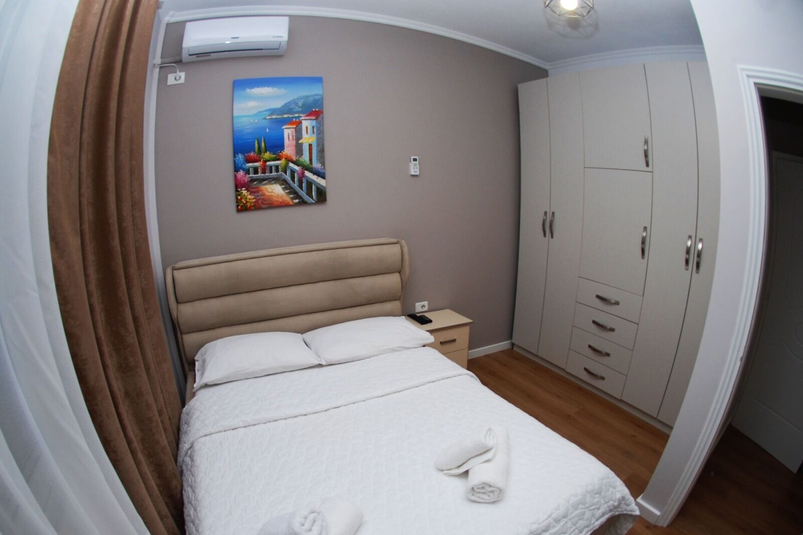 Ein Schlafzimmer mit Bett, Nachttisch, Kleiderschrank und einem Gemälde an der Wand.