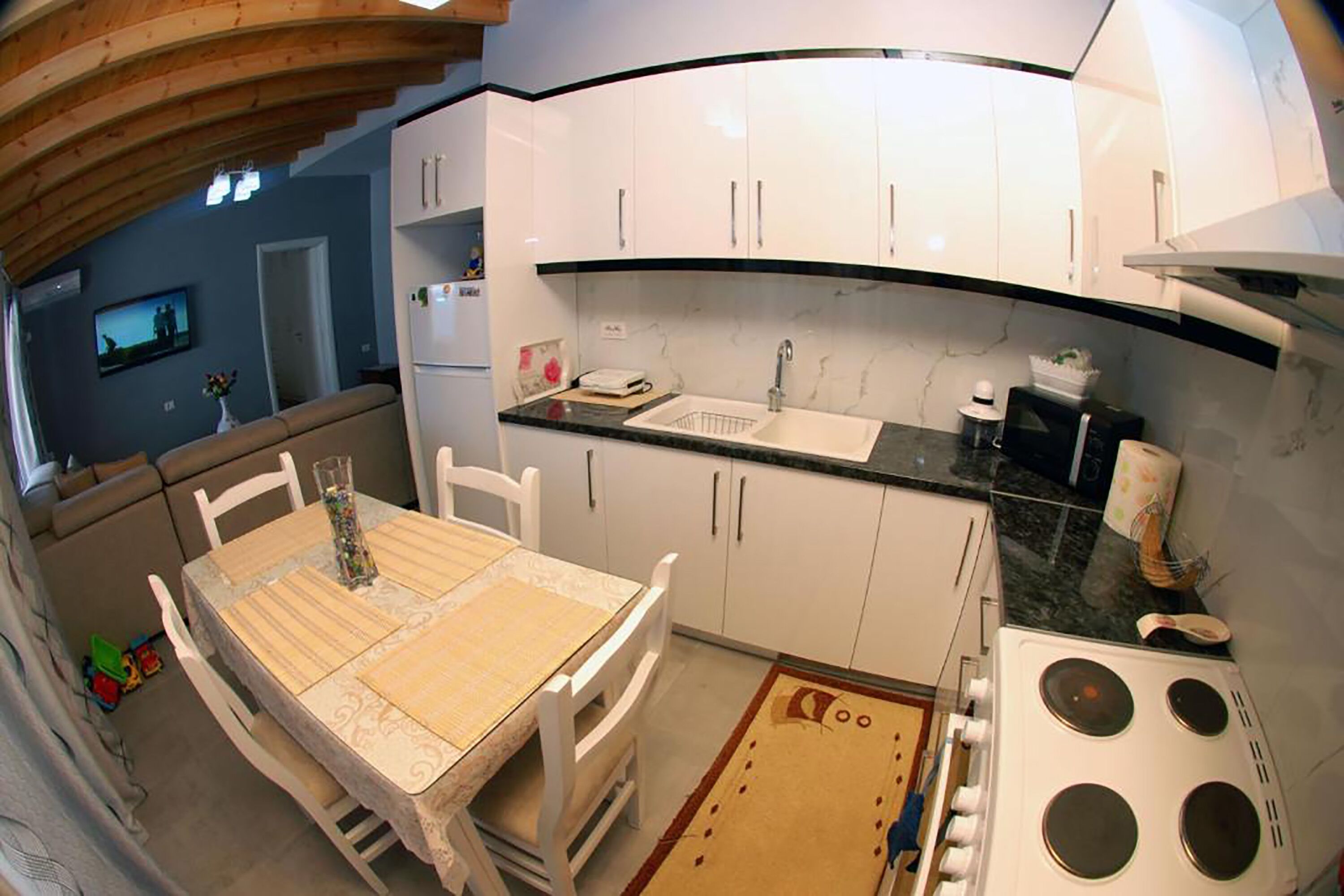 A compact kitchen with white cabinets, a sink, and a stove.
