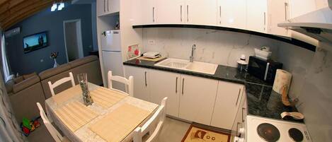 A compact kitchen with white cabinets, a sink, and a stove.