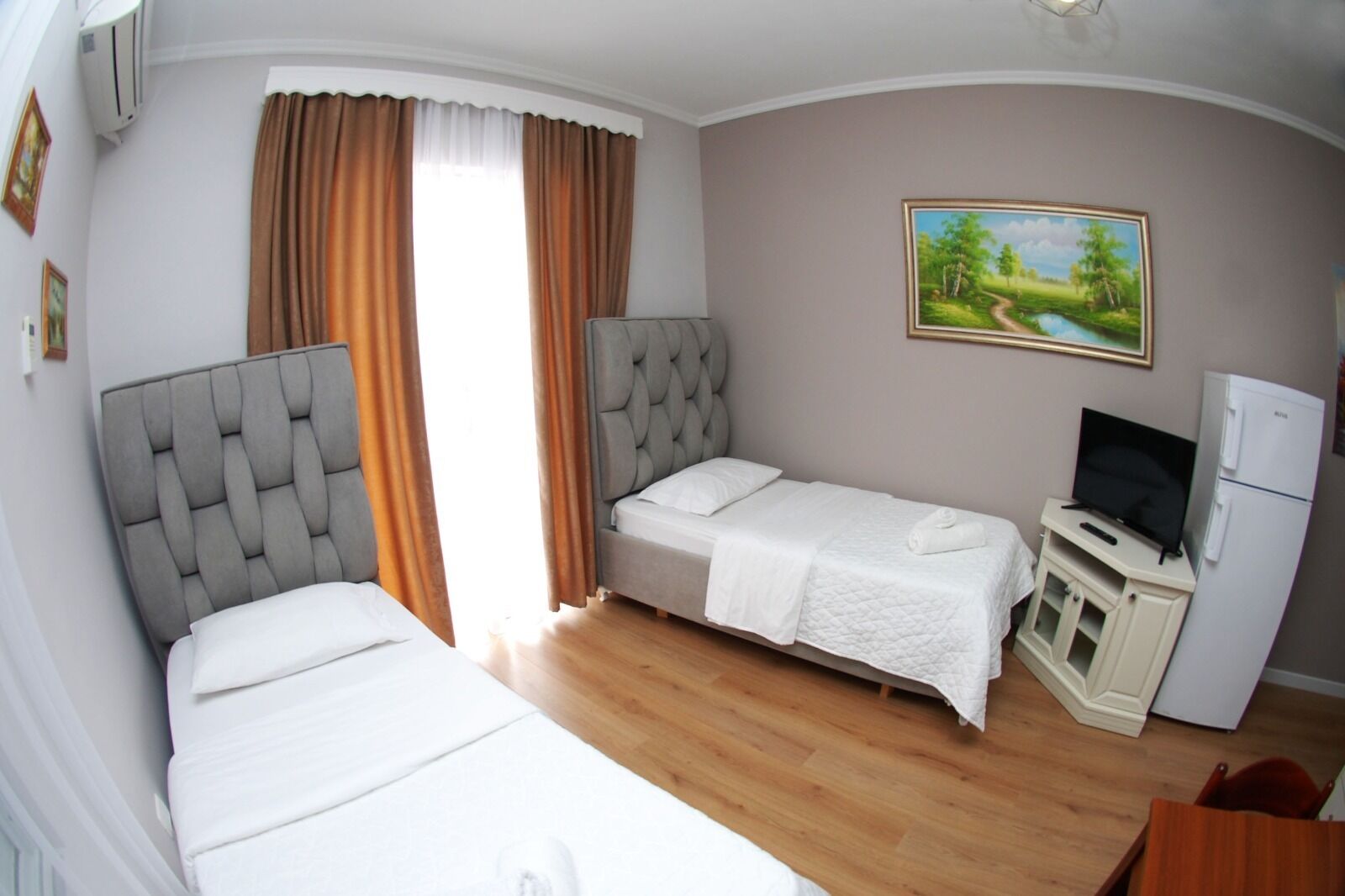 Une chambre d’hôtel avec deux lits, une télévision et un réfrigérateur.
