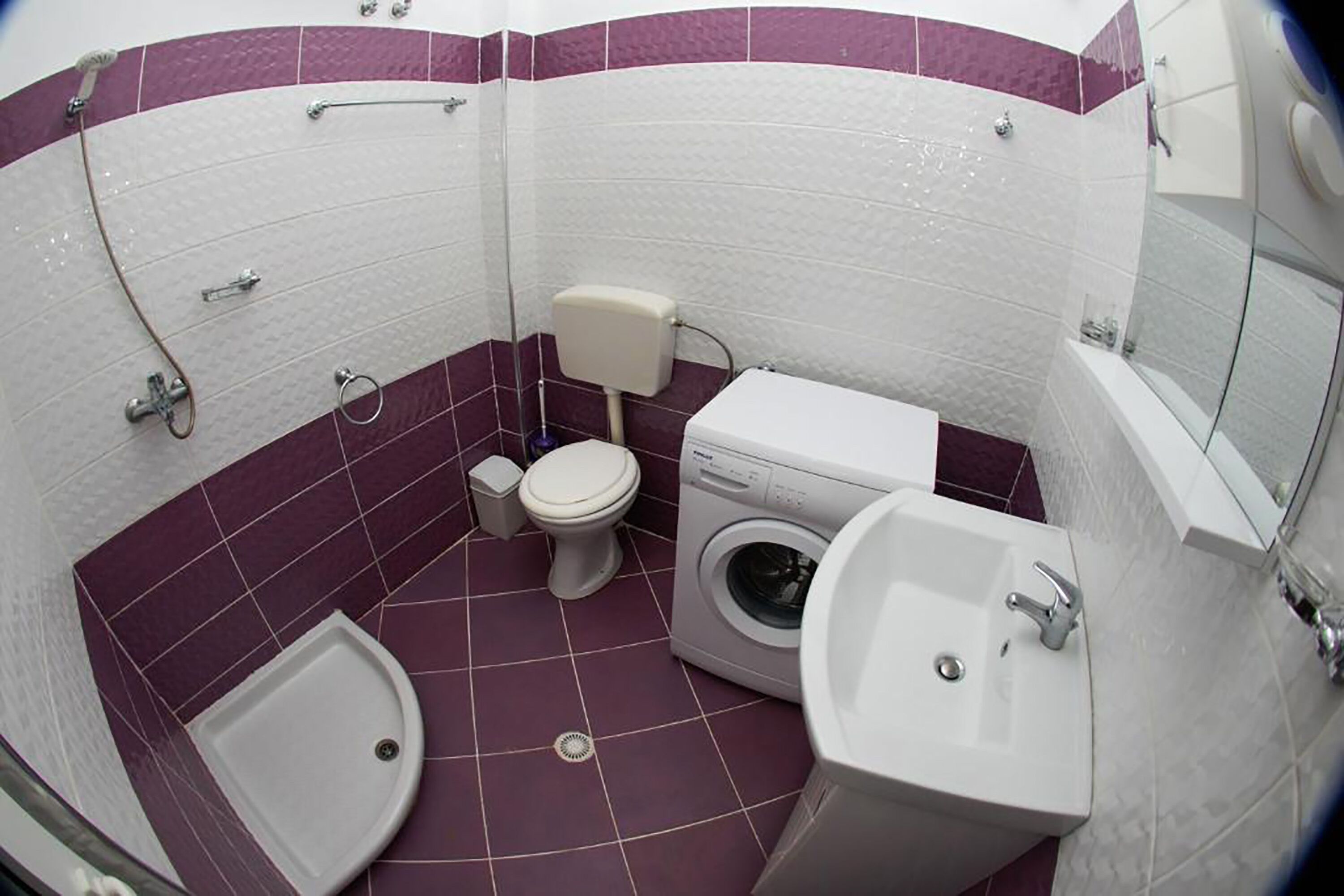 A compact bathroom with a toilet, washing machine, bidet, and sink.