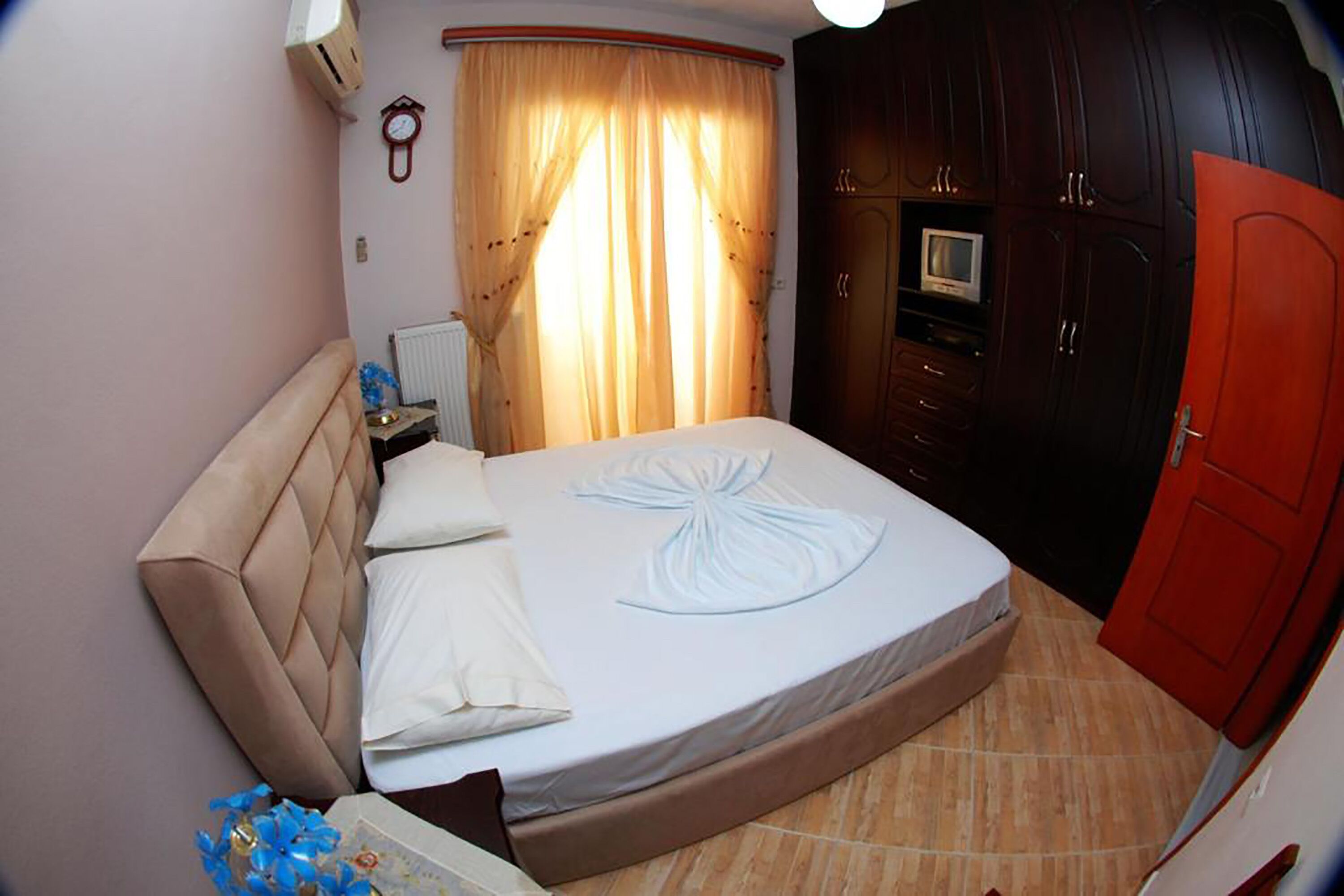 A bedroom with a bed, a nightstand, a TV, and a wardrobe.