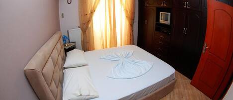 A bedroom with a bed, a nightstand, a TV, and a wardrobe.