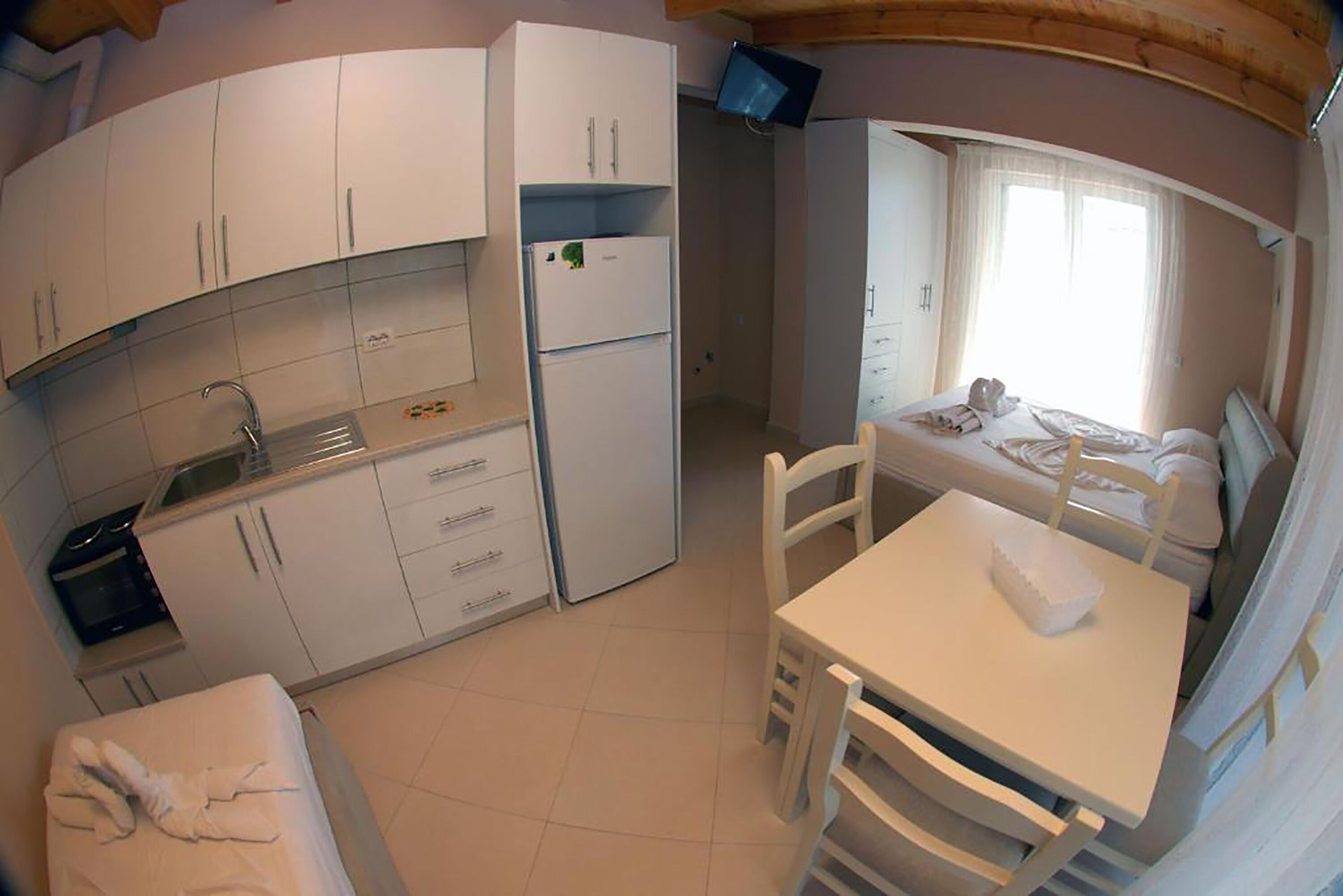 A compact kitchen with white cabinets, a refrigerator, and a dining area with a table and chairs.