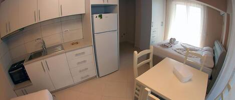 A compact kitchen with white cabinets, a refrigerator, and a dining area with a table and chairs.