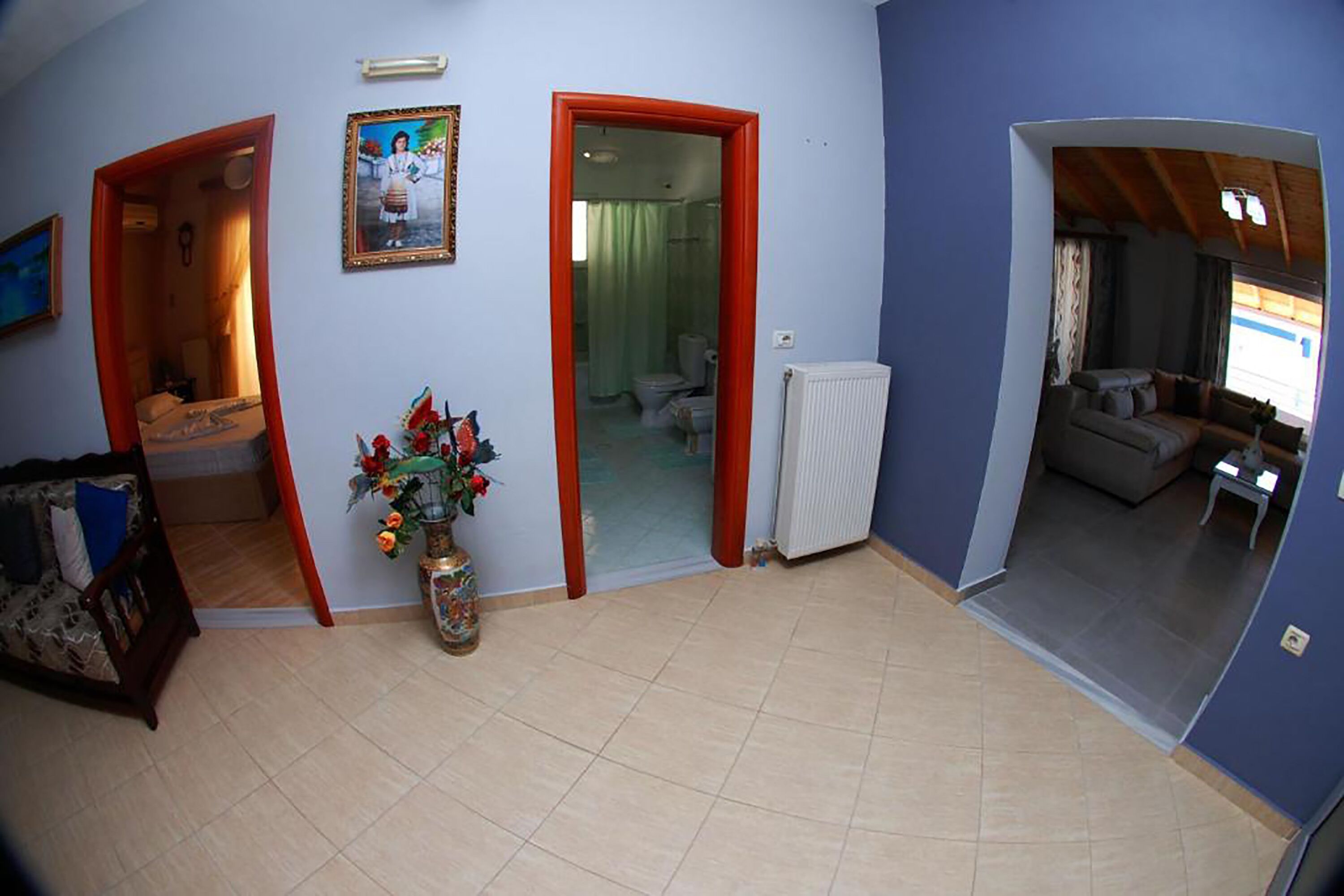 A room with a tiled floor, a wooden door, a radiator, and a sofa.