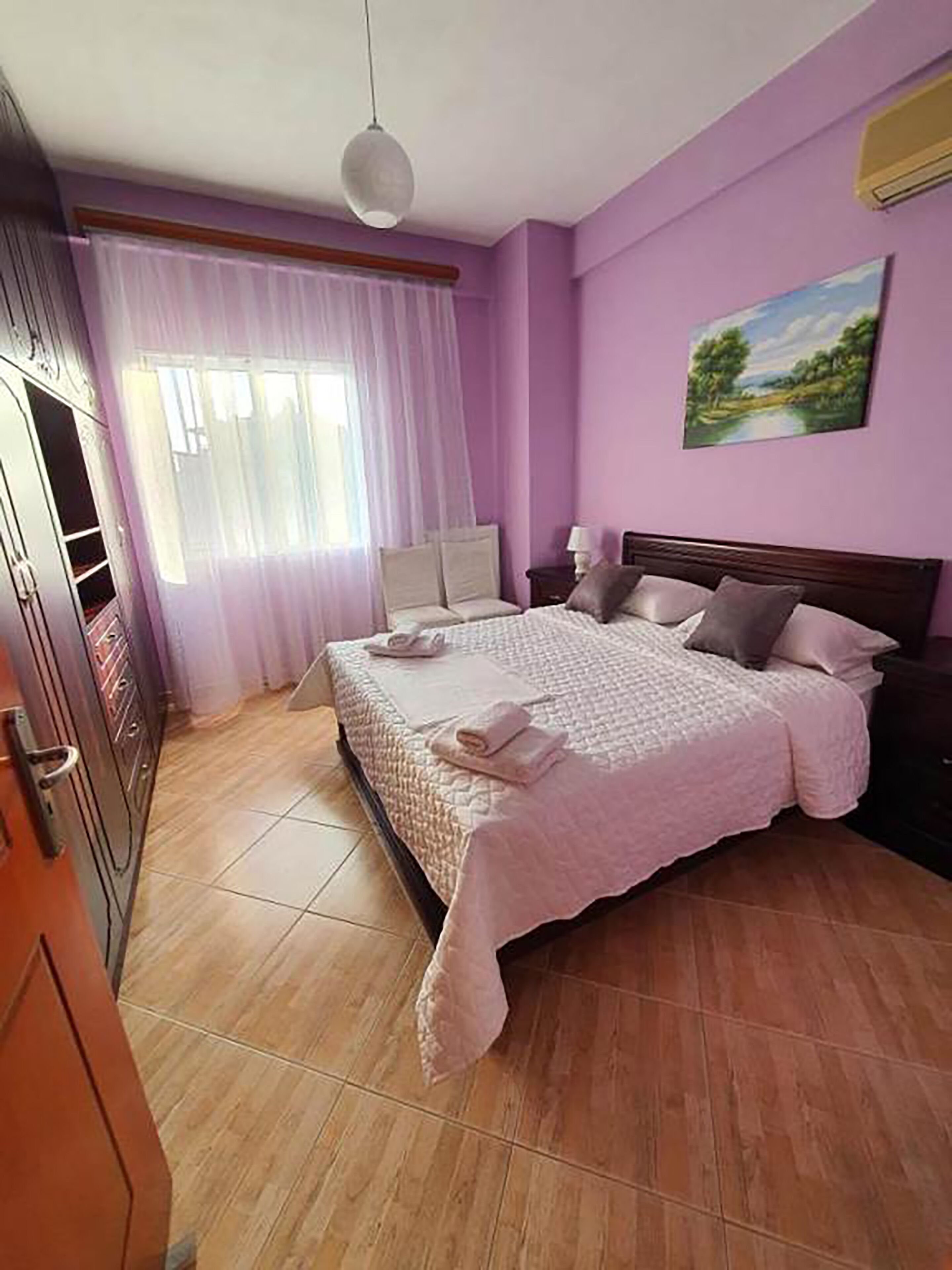 Un dormitorio con una cama, una mesita de noche, un cuadro en la pared y un armario.