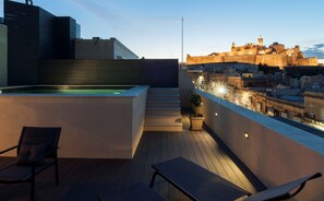 A rooftop terrace with a hot tub, lounge chairs, and a view of a historic city wall at dusk. - The Duke Boutique Hotel (Victoria)