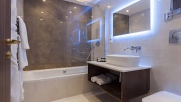 Un baño moderno con ducha envuelta en vidrio, un lavamanos blanco y un espejo grande.