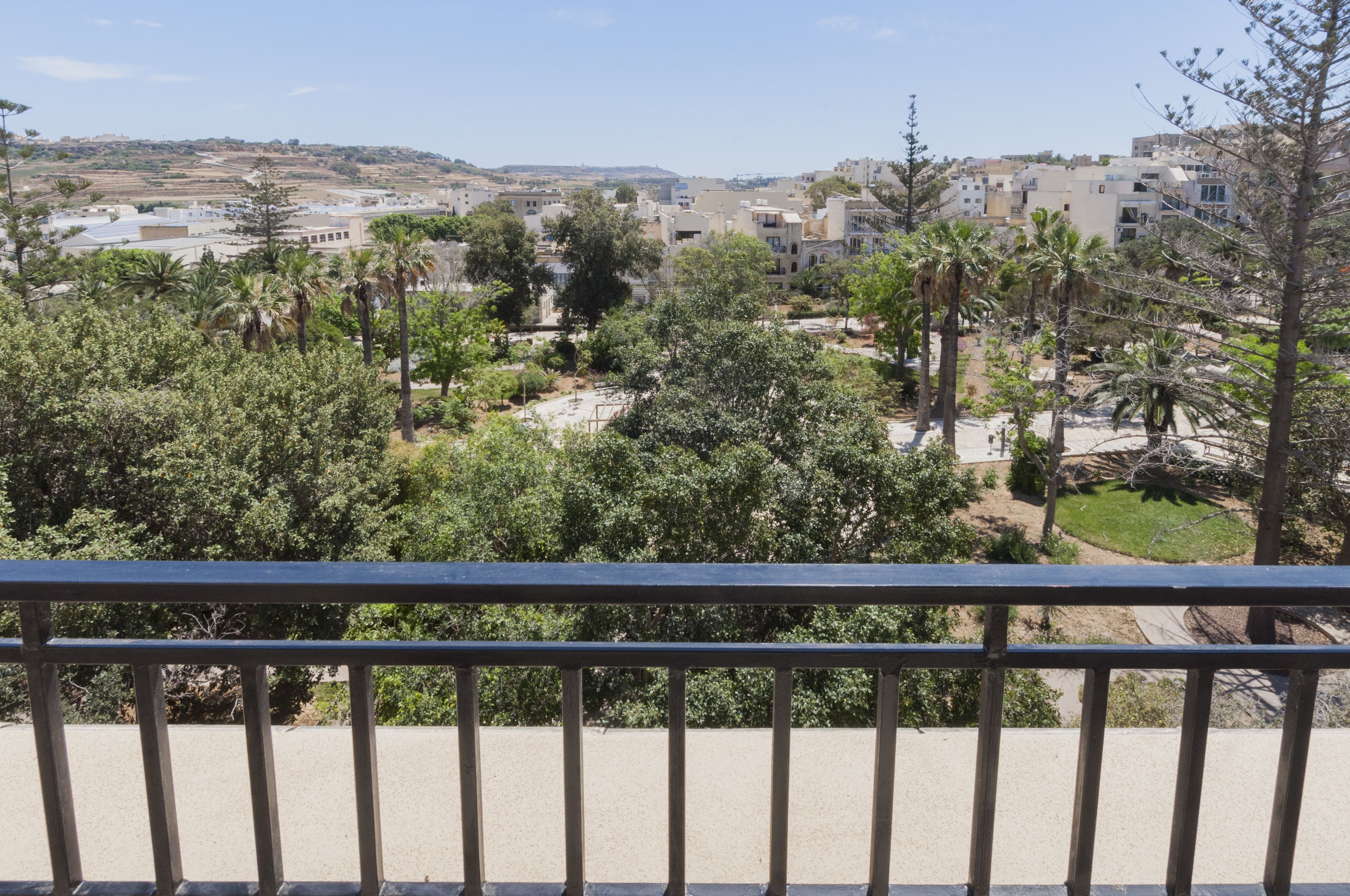 A balcony with a view of a residential area, including houses and greenery.