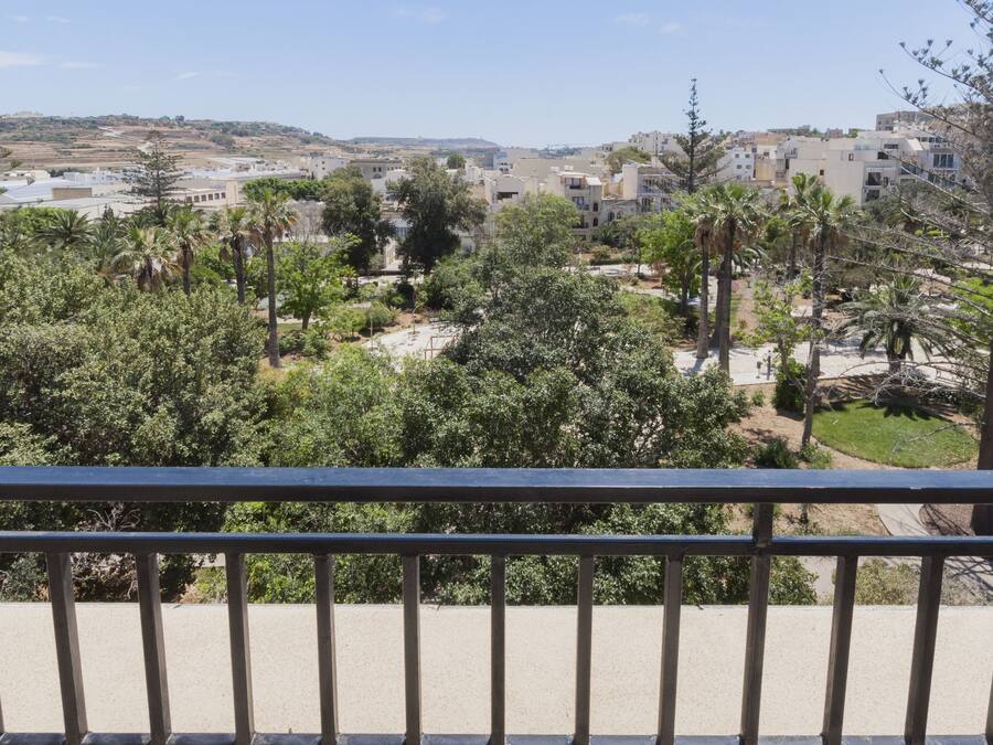 A balcony with a view of a residential area, including houses and greenery.