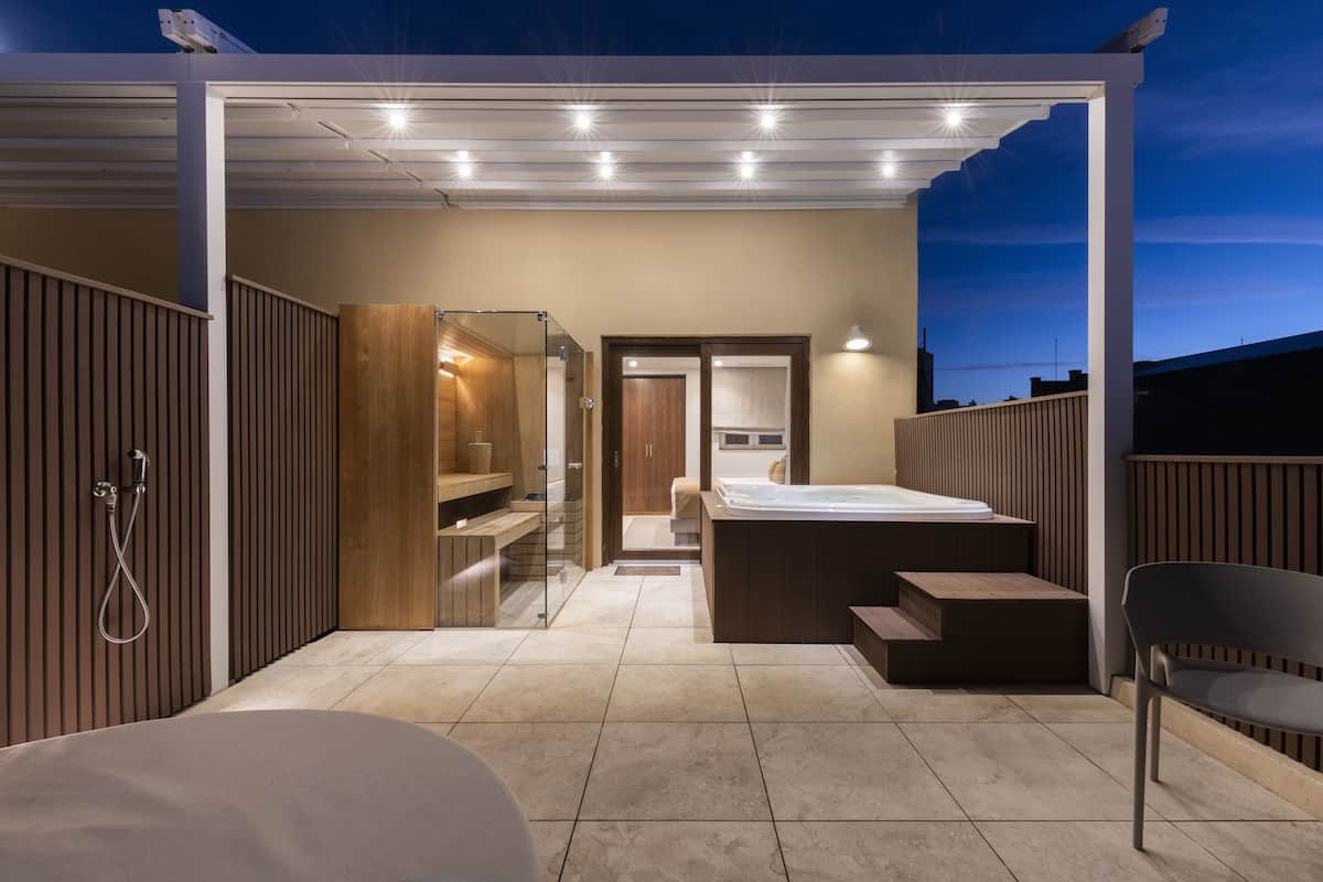 A modern, well-lit bedroom with a large bed, a walk-in closet, and a bathroom with a glass shower enclosure.