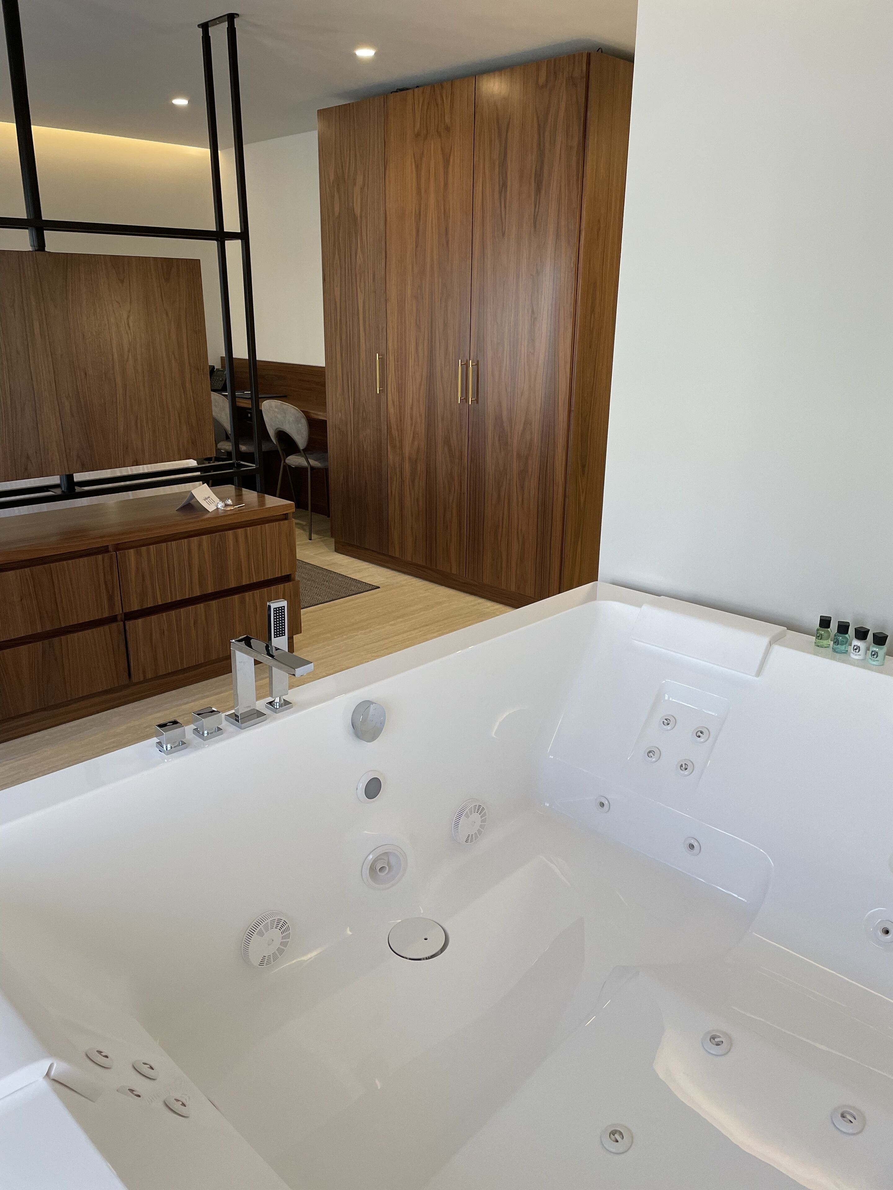 Une salle de bain moderne avec une grande baignoire blanche, des meubles en bois et un petit bureau avec un téléphone.