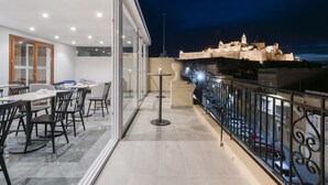 A balcony with a dining area, a table with chairs, and a view of a historic building at night. - The Duke Boutique Hotel (Victoria)