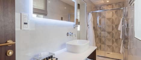 A modern bathroom with a large mirror, a white sink, and a glass-enclosed shower.