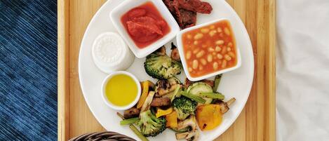 A breakfast tray with toast, beans, roasted vegetables, and a cup of coffee.