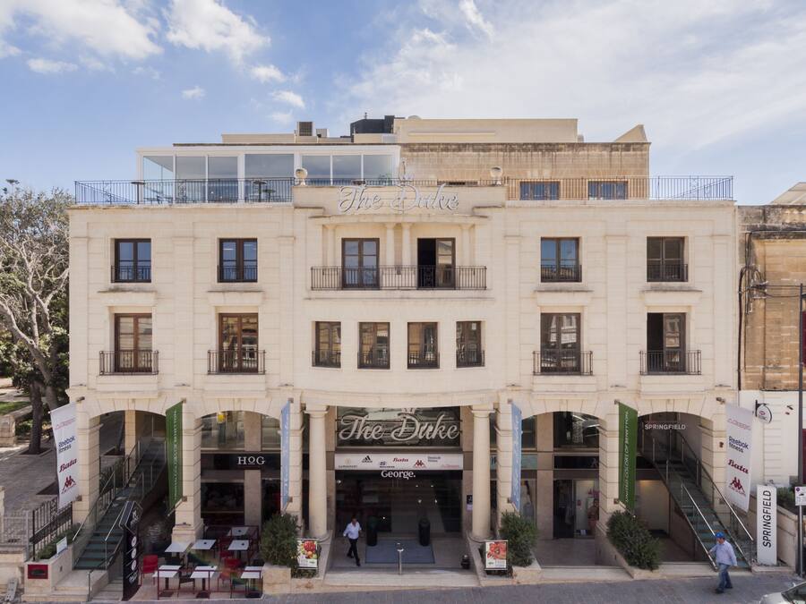 Un hotel con una entrada destacada, varios balcones y un letrero que dice "The Duke".