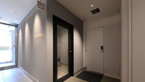 Um lobby de hotel moderno com um balcão de recepção, uma área reservada para fumantes e uma porta que dá para um quarto.