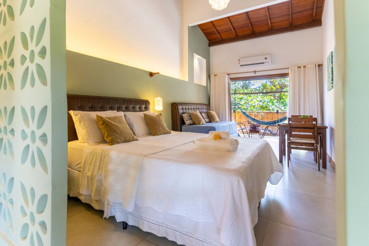 A bedroom with two beds, a hammock, and a dining area.
