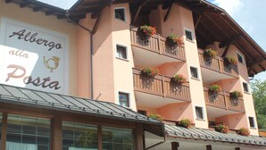 A multi-story building with balconies adorned with flower boxes. - Albergo Alla Posta (Pinzolo)