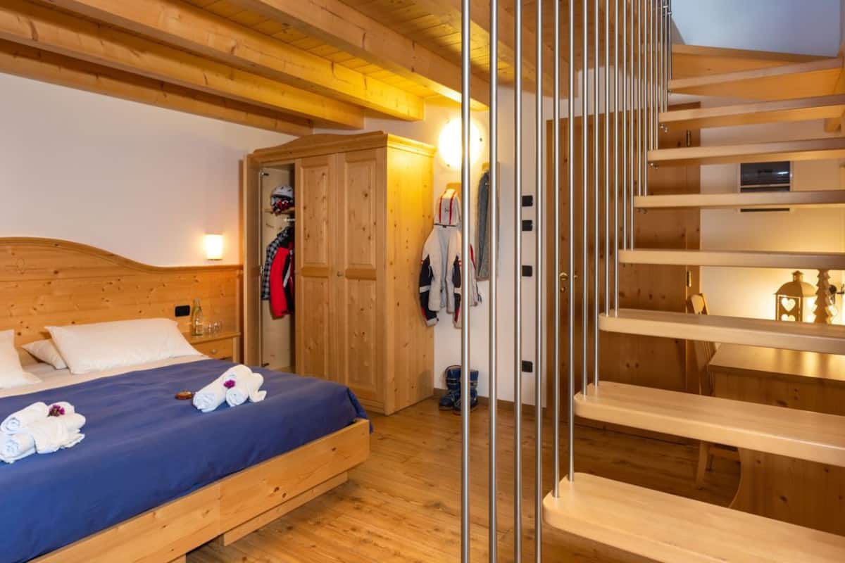 A wooden bedroom with a bed, a wardrobe, and a built-in shelf unit.
