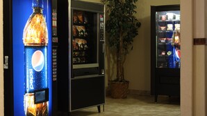 A vending machine area with a Pepsi dispenser, a refrigerator, and a potted plant. - Sunset Inn and Suites (Sioux Lookout)