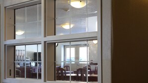 A window with multiple panes, a kitchen area with cabinets and appliances, and a dining area with chairs and tables. - Sunset Inn and Suites (Sioux Lookout)