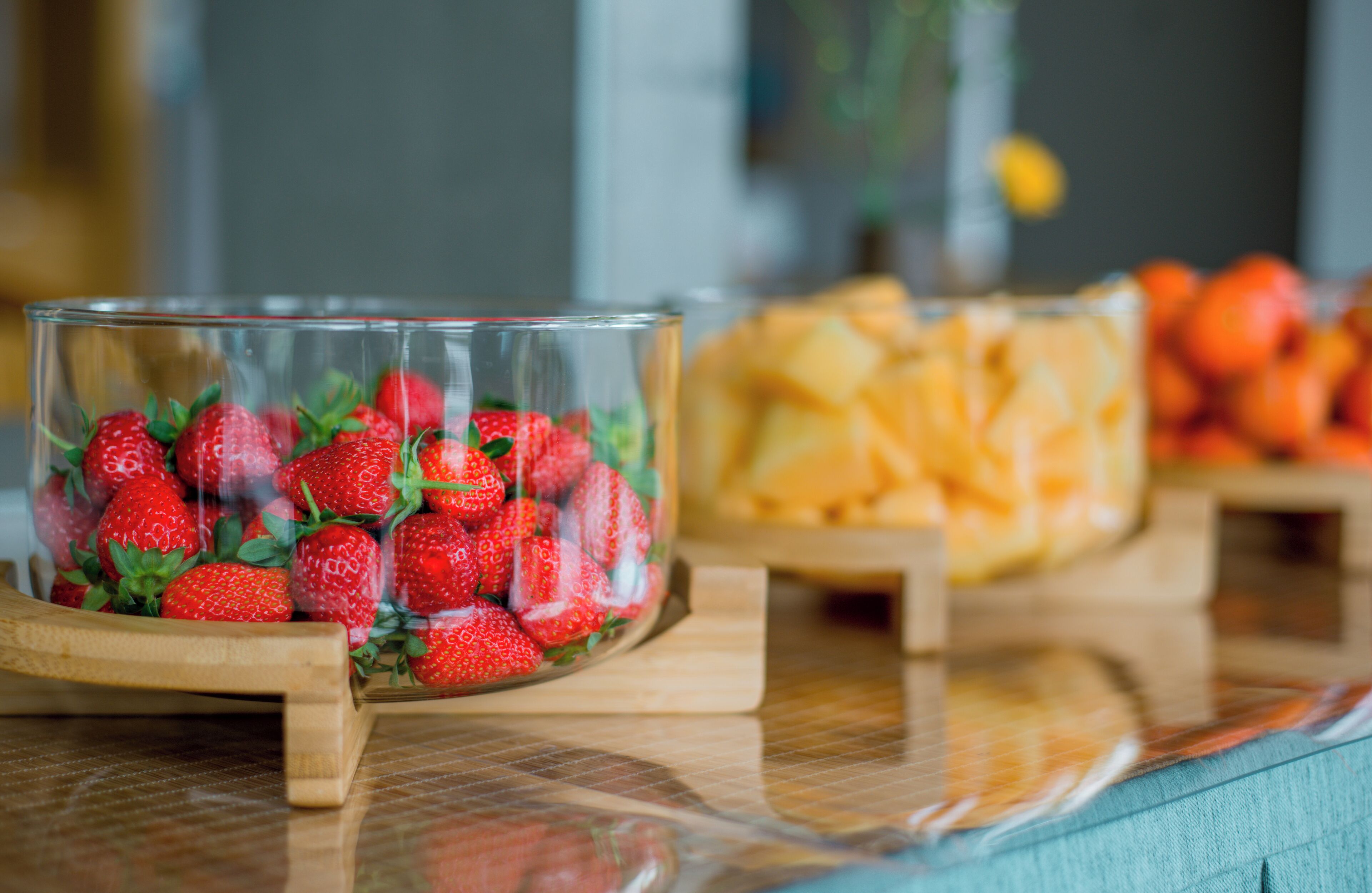 A glass bowl filled with strawberries on a wooden stand.