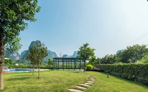A well-maintained garden with a swimming pool, a glass-enclosed structure, and a stone pathway.