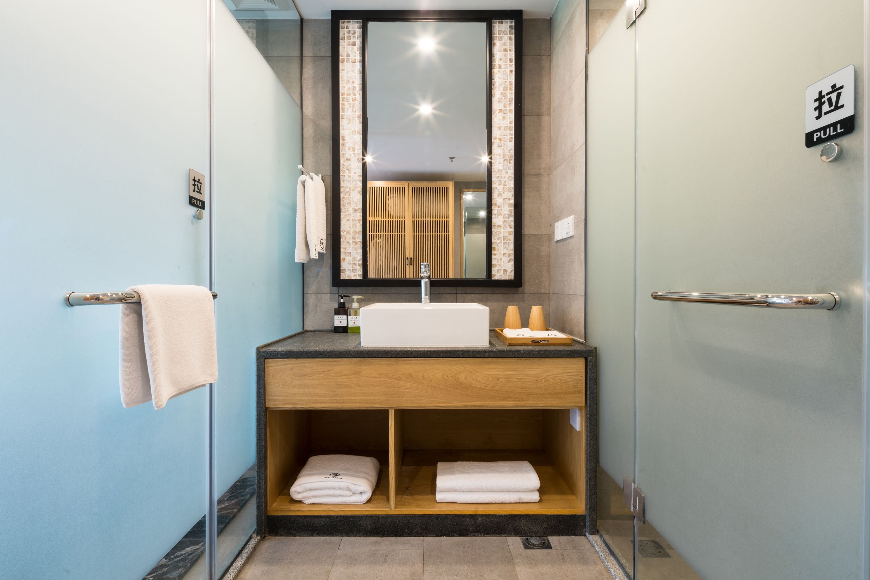 A modern bathroom with a sink, mirror, and towel rack.