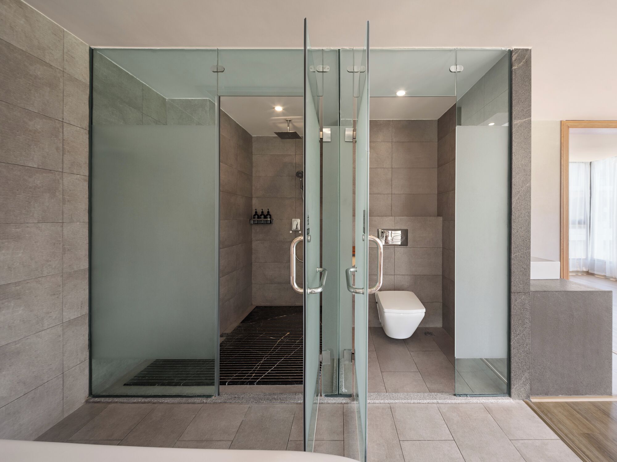 A modern bathroom with a glass-enclosed shower, a toilet, and a sink.