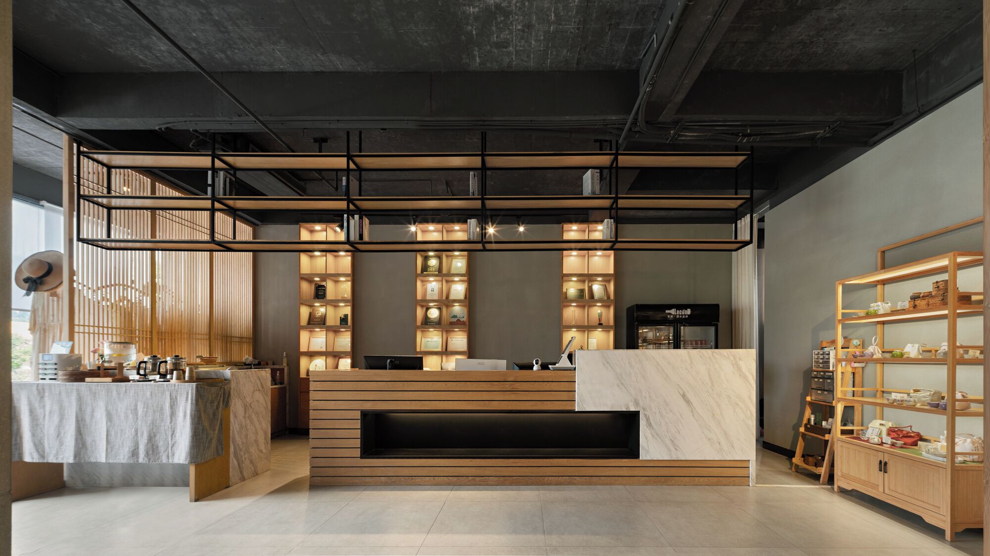A modern reception area with a wooden reception desk, a coffee machine, and a display of awards.