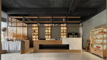 A modern reception area with a wooden reception desk, a coffee machine, and a display of awards.