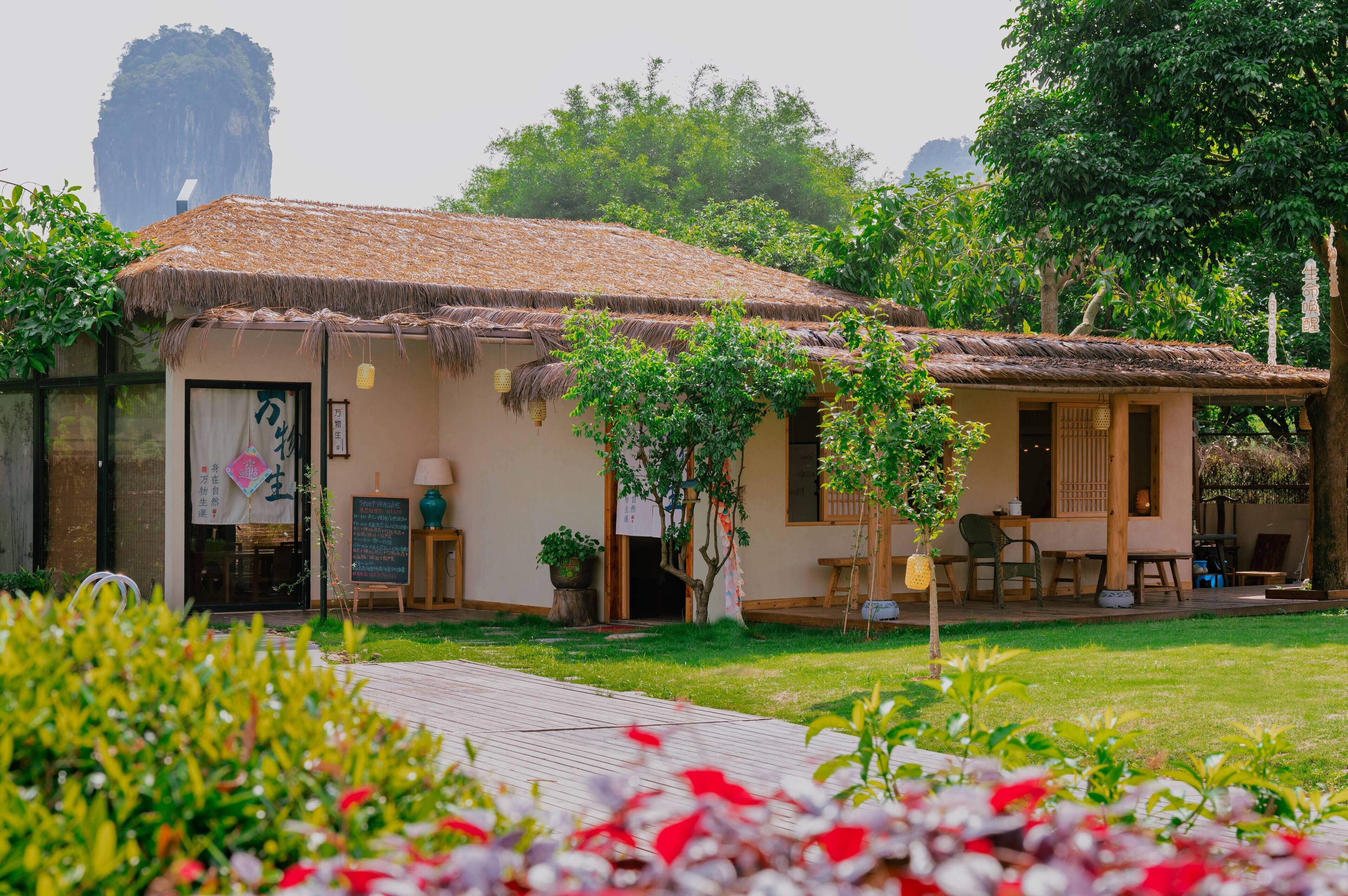 A traditional-style building with a thatched roof, a small garden area, and a wooden deck.