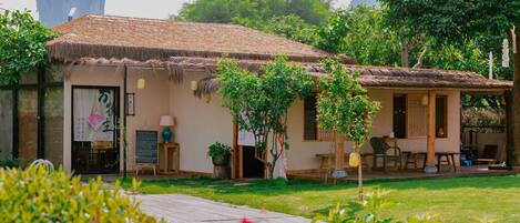 A traditional-style building with a thatched roof, a small garden area, and a wooden deck.