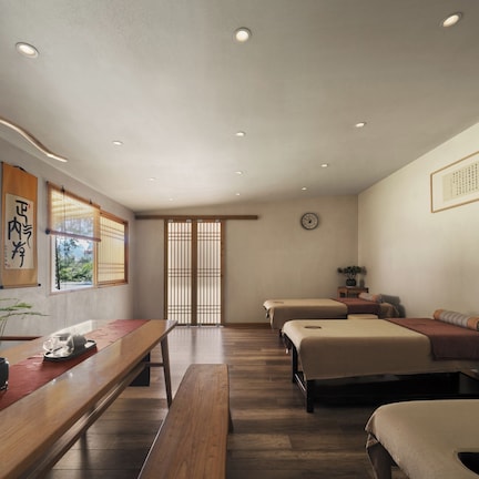 A traditional Japanese-style room with tatami flooring, a low wooden table, two tatami beds, and a shoji screen door.