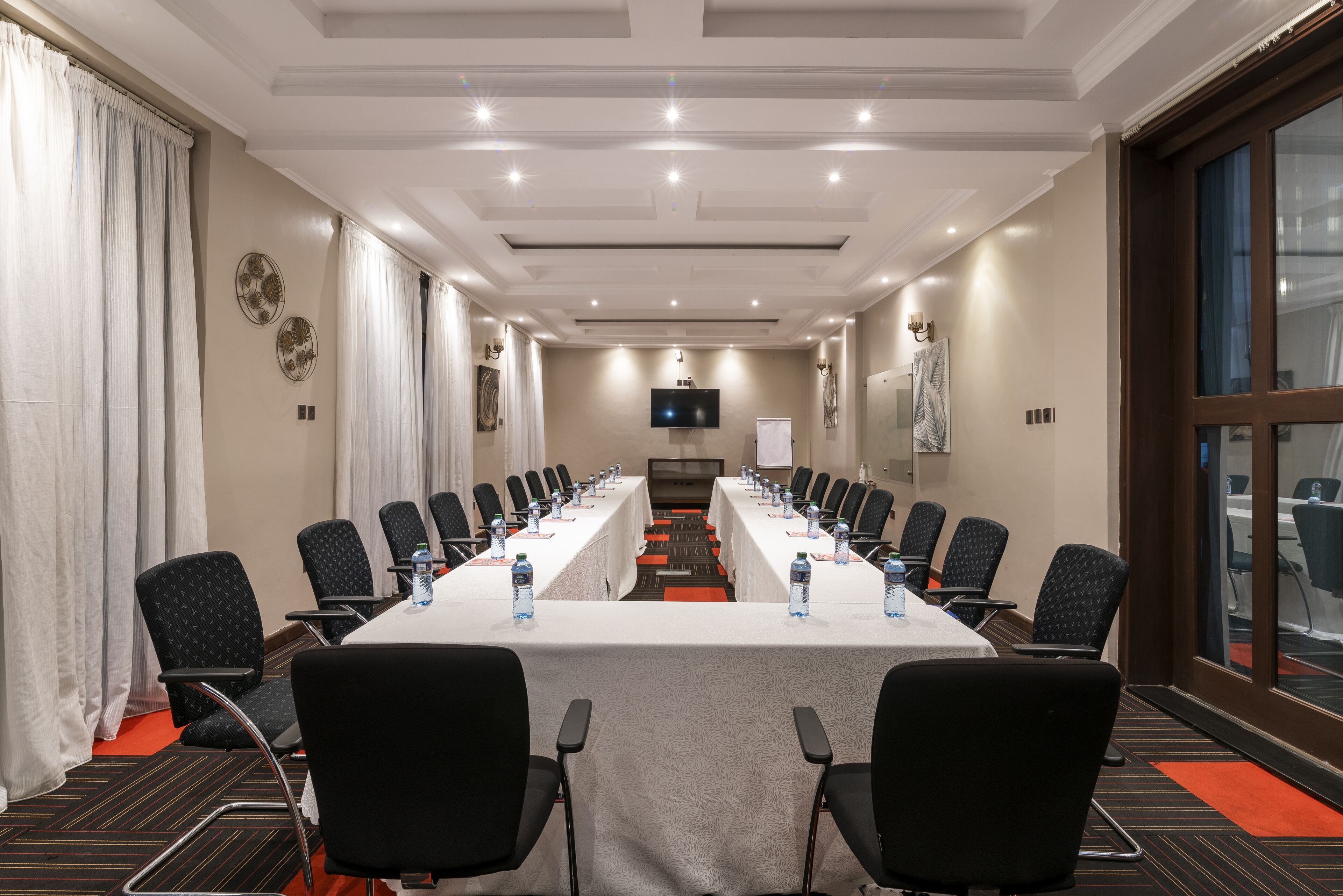 A conference room with a long table, chairs, and a television screen.