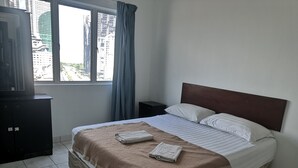 A hotel room with a large bed, a TV on a cabinet, and a window with curtains. - Globallon Hotel Apartment (Malacca City)