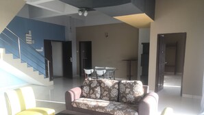 A spacious living area with a sofa, two chairs, a coffee table, and a staircase. - Globallon Hotel Apartment (Malacca City)
