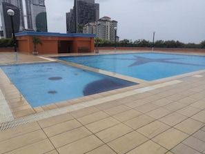 A swimming pool with a tiled deck and a small building with a blue roof. - Globallon Hotel Apartment (Malacca City)