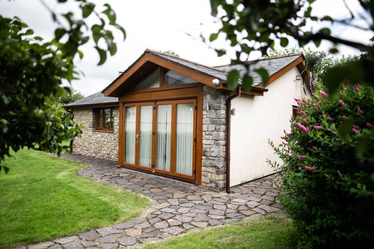 A house with a stone facade, a wooden front door, and a stone pathway leading to the entrance.
