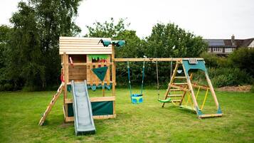 Kids can play on the slide, swing set, and climbing wall in this backyard play area.